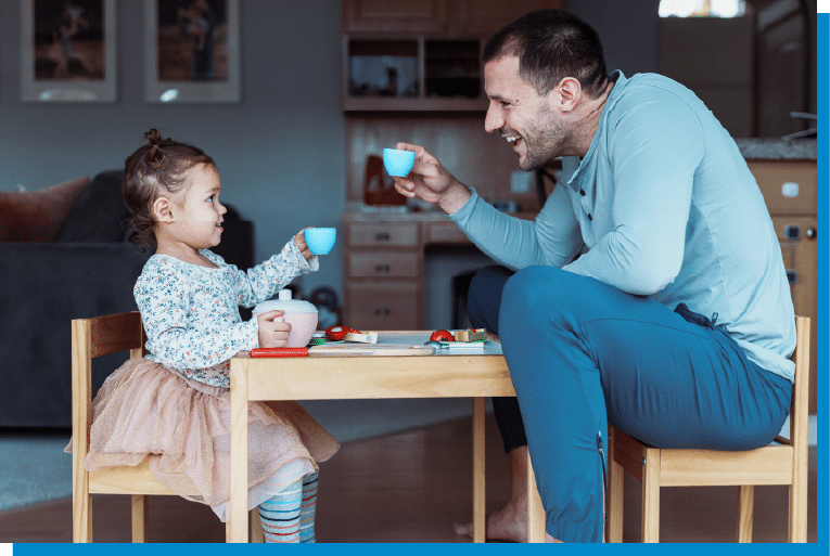 Father and daughter enjoying a playful pretend tea party at a small table