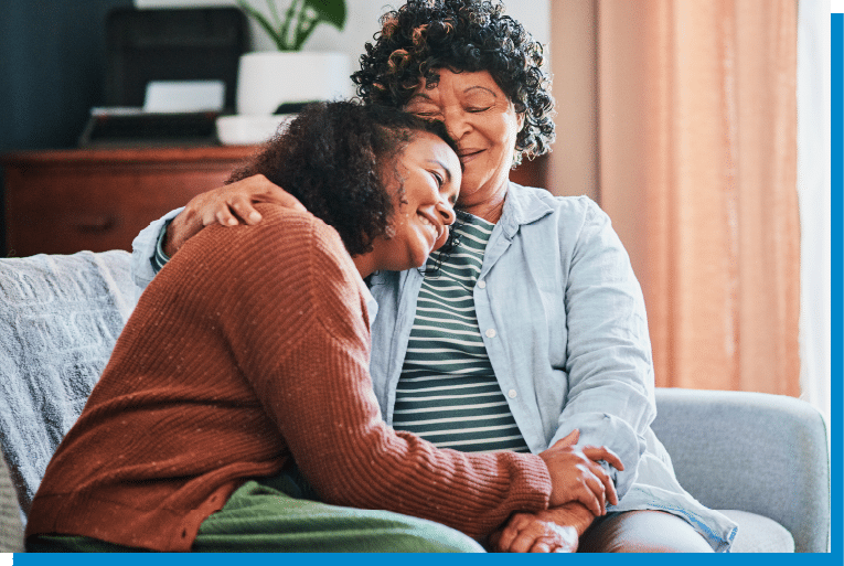 Mother and adult daughter sharing a warm hug on the living room couch