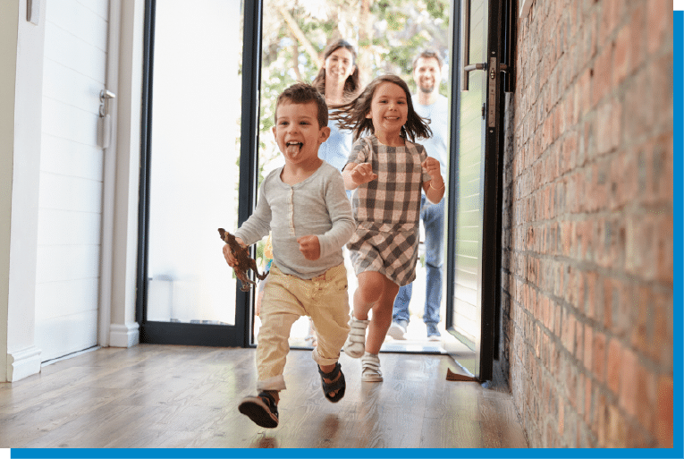 Two excited children running into the house while their parents smile at the doorway
