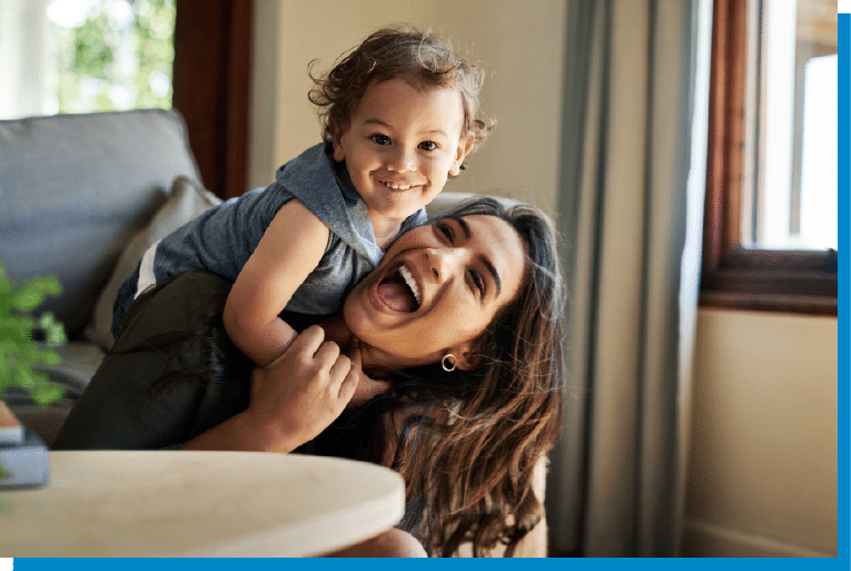 Mother laughing while playing with her smiling toddler at home