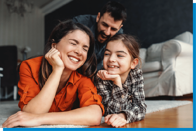 Happy family laughing together while relaxing on the living room floor at home