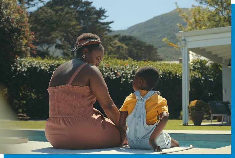 Mother and child relaxing together outdoors on a sunny day near the pool
