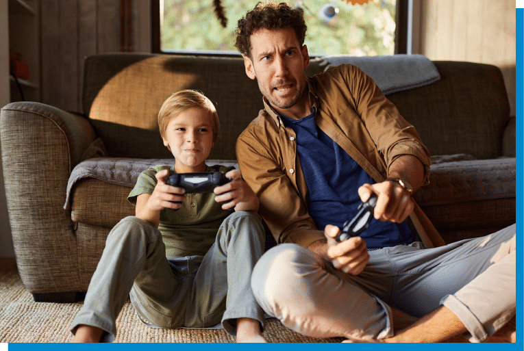 Father and son sitting on the floor playing video games together in the living room