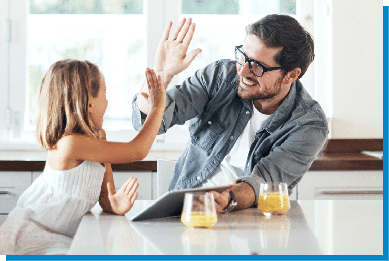 Father and daughter smiling and giving a high-five at the kitchen counter