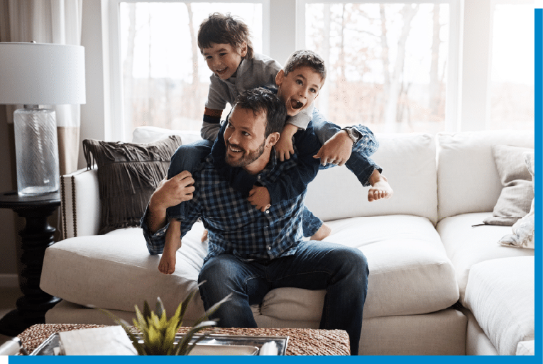 Father playing with his two sons on the living room couch, enjoying a fun family moment