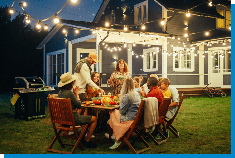 Family and friends enjoying an outdoor dinner under string lights in the backyard