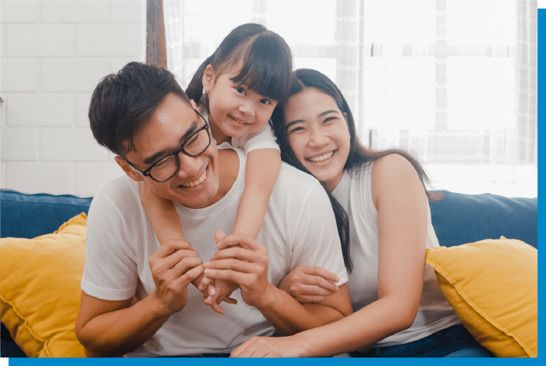 Happy family smiling together on the couch as their daughter hugs her parents
