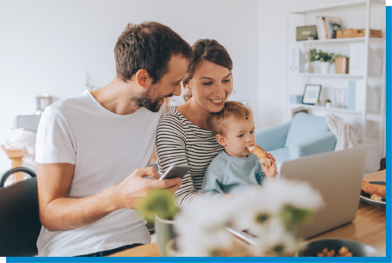 Young family enjoying breakfast together while using a laptop at home